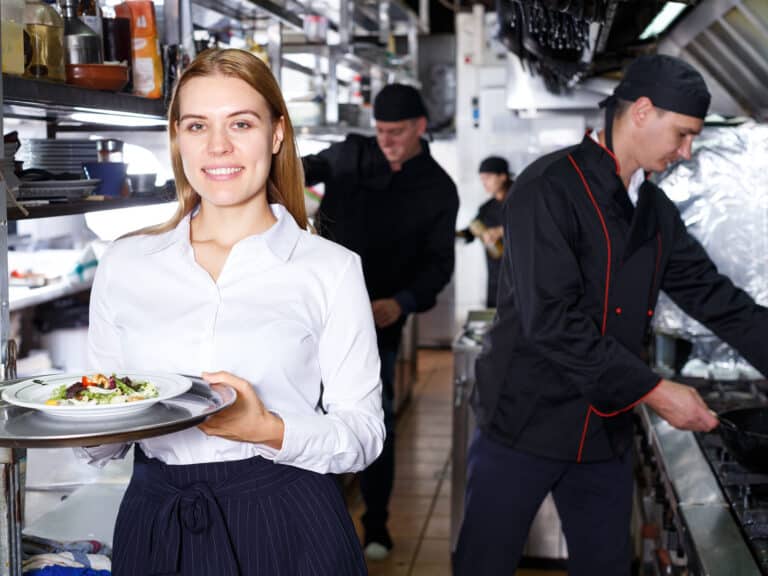 Waitress with tray standing at restaurant kitchen
